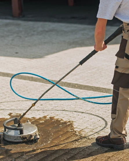 Professionele reiniging van een bestrate oprit met een oppervlaktecleaner.